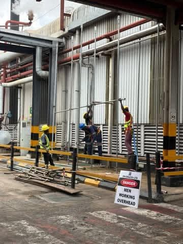 Crew working at pipework beside a danger sign