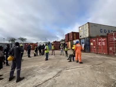 Crew gathered beside shipping containers for a briefing