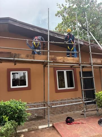 Two workers on scaffold at the eaves of a bungalow