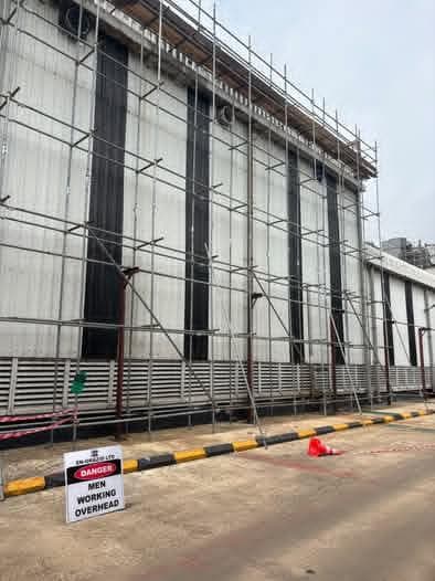 Scaffold rising against the plant facade, with a danger sign at its base