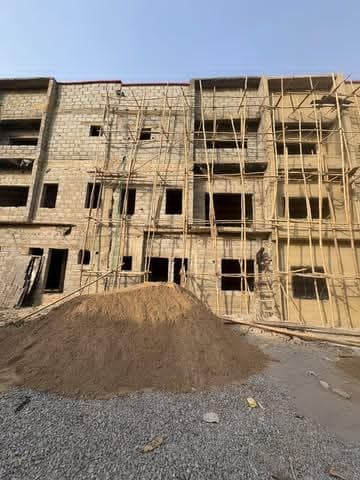 Block walls rising behind a heap of sharp sand