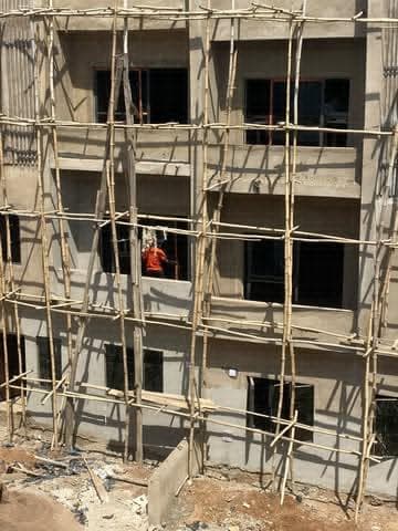 Window openings framed by bamboo scaffolding on the upper floors